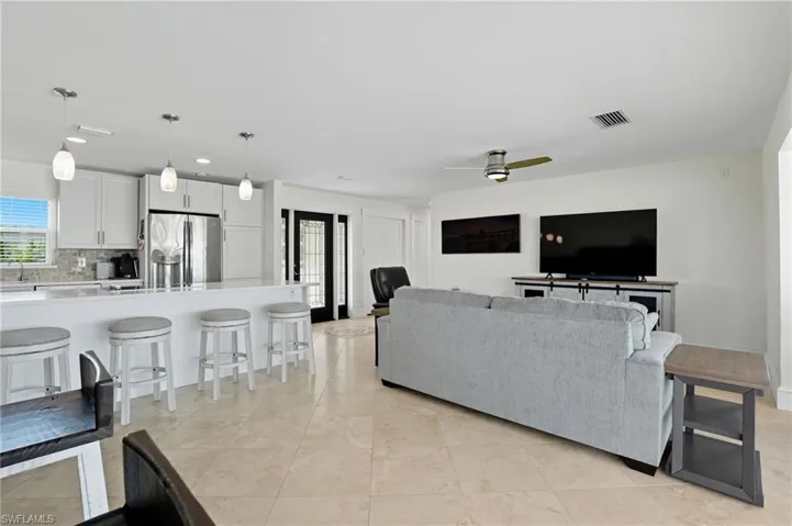 Living room with light tile patterned floors, recessed lighting, a ceiling fan, and french doors - Virtually Edited Image