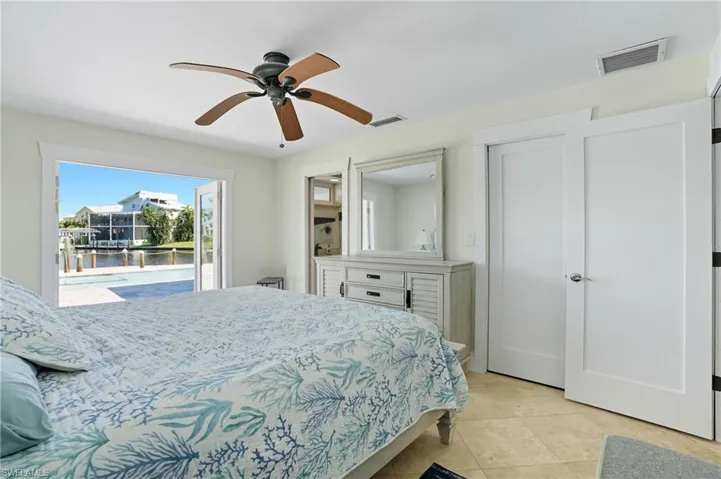 Bedroom featuring access to exterior, a water view, light tile patterned floors, and ceiling fan - Virtually Edited Image
