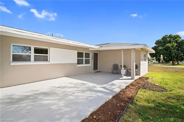 Exterior facade with a covered entry, neutral stucco finish, white-framed windows, white fascia, and a gabled roof
