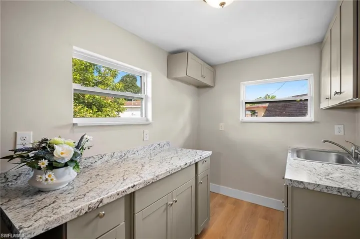 Kitchen featuring light wood-finish flooring, light gray cabinetry, and patterned countertops