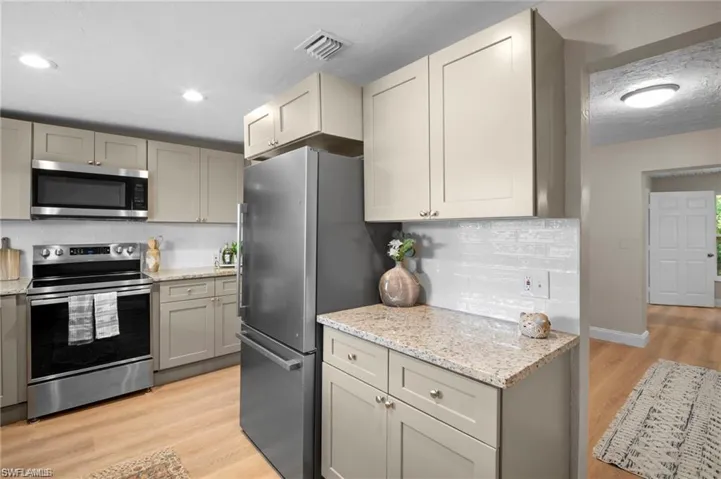 Kitchen featuring stainless steel appliances, light wood-finish flooring, recessed lighting, and granite countertops