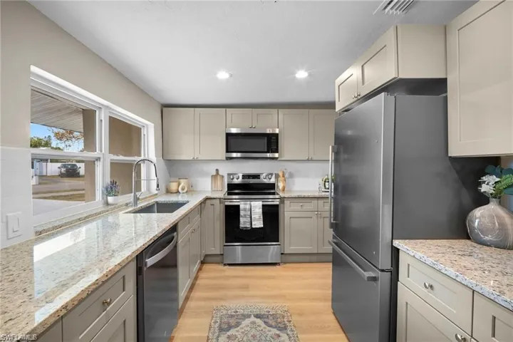 Kitchen featuring wood-finish flooring, light cabinetry, and light-toned countertops