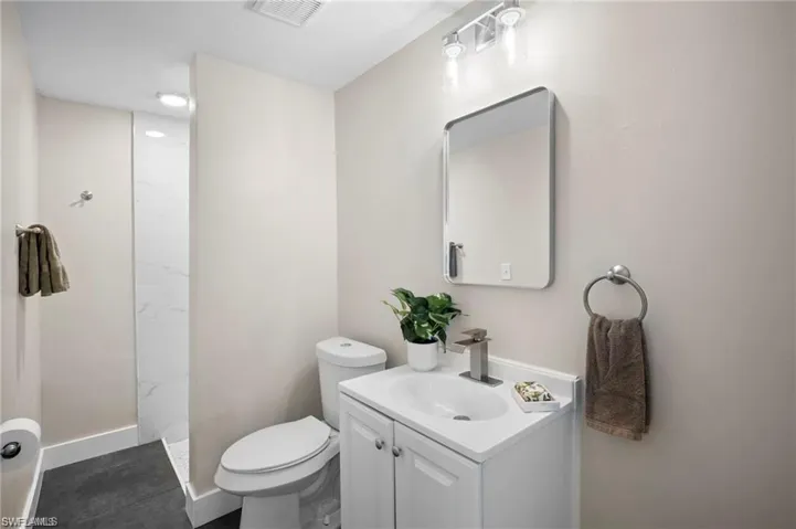 Bathroom featuring a white vanity with integrated sink, brushed nickel faucet, and a wall-mounted mirror