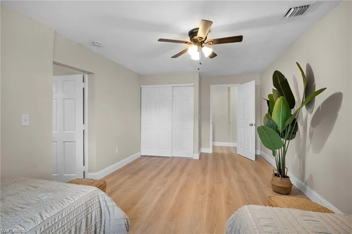 Spacious interior room featuring wood-finish flooring, light-toned walls, and a ceiling fan with integrated lighting