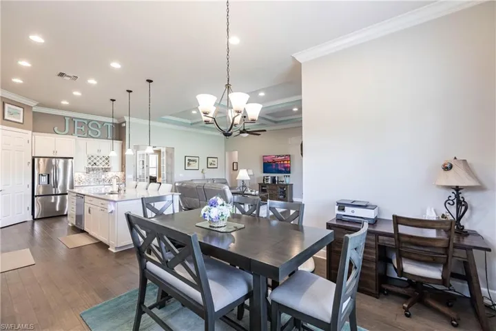 Dining area with crown molding, sink, dark wood-type flooring, and a chandelier