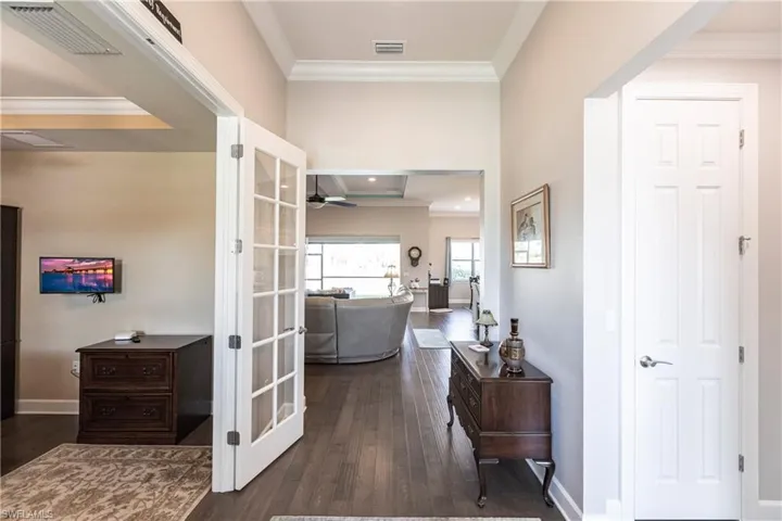 Corridor with ornamental molding, dark wood-type flooring, and french doors