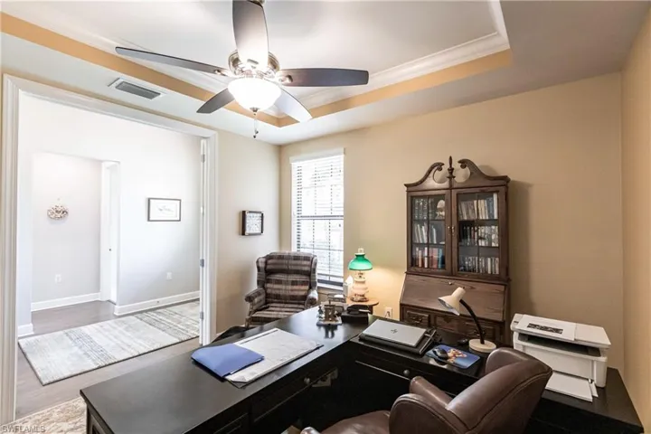 Office space with ornamental molding, a tray ceiling, ceiling fan, and hardwood / wood-style floors