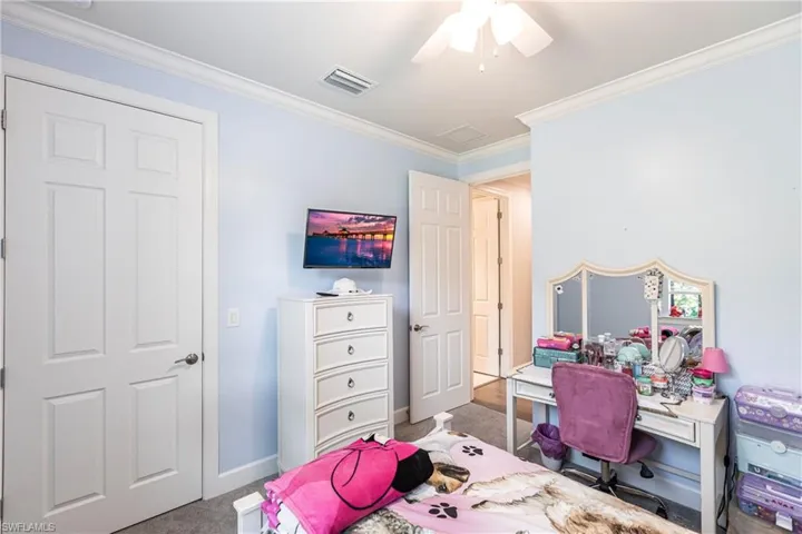 Carpeted bedroom with ornamental molding and ceiling fan