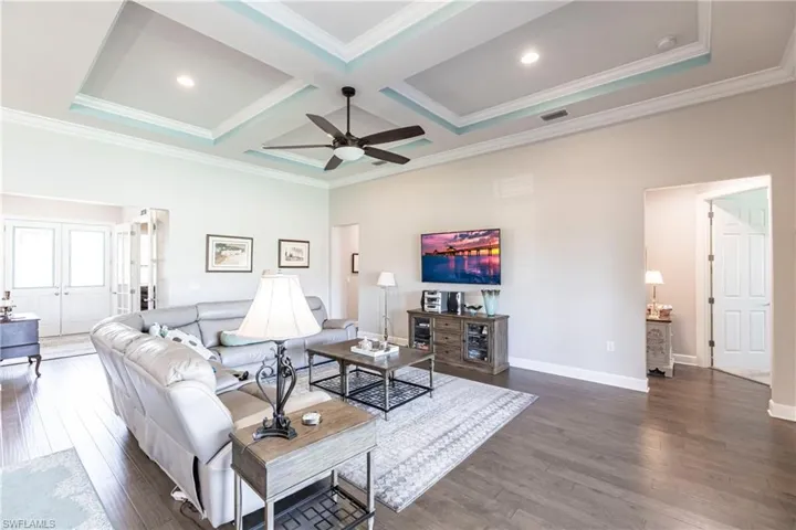 Living room with ceiling fan, dark hardwood / wood-style floors, ornamental molding, and coffered ceiling