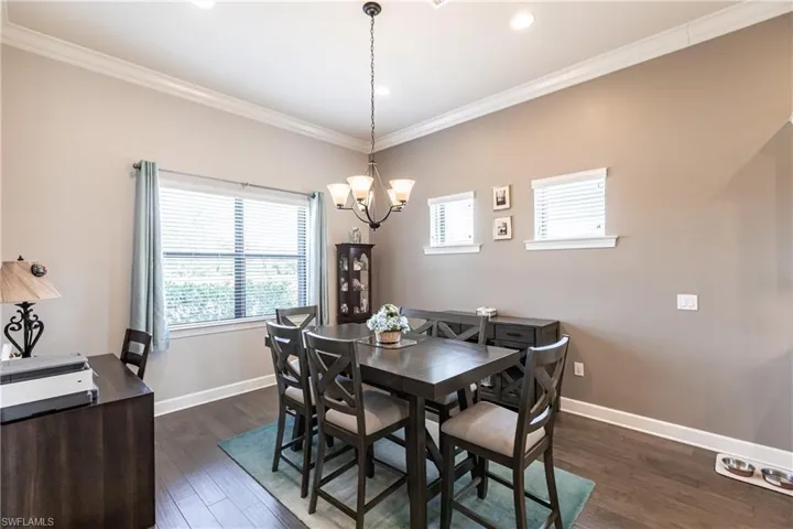 Dining room featuring crown molding, dark hardwood / wood-style flooring, a chandelier, and a wealth of natural light