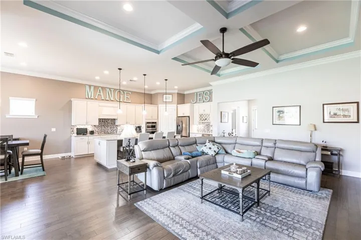 Living room featuring ceiling fan, beam ceiling, ornamental molding, coffered ceiling, and dark hardwood / wood-style floors