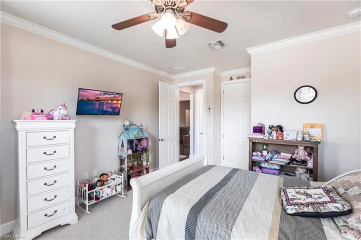 Carpeted bedroom featuring crown molding and ceiling fan