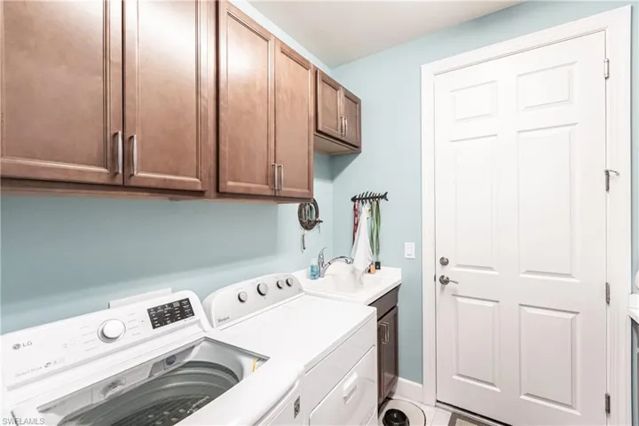 Washroom featuring cabinets, tile patterned floors, washer and clothes dryer, and sink