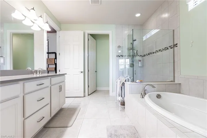 Bathroom with independent shower and bath, vanity, and tile patterned floors