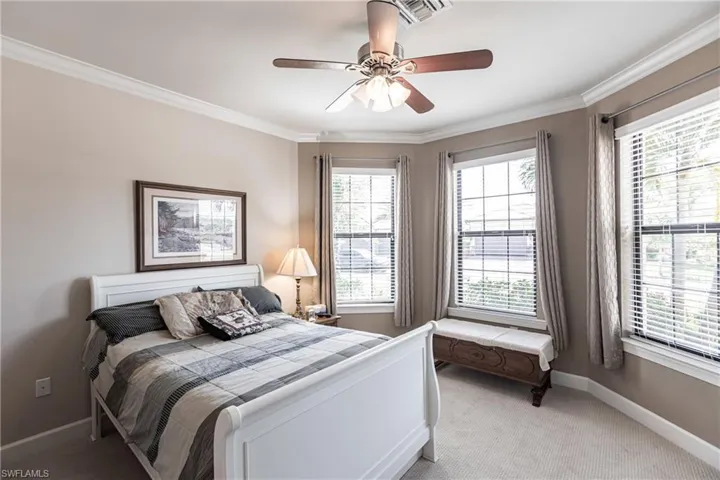 Bedroom featuring multiple windows, crown molding, light carpet, and ceiling fan
