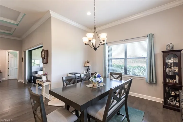 Dining space featuring an inviting chandelier, ornamental molding, and dark wood-type flooring