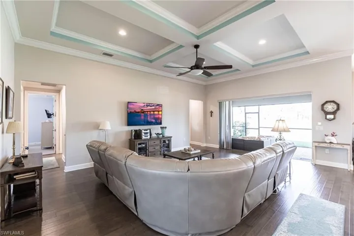 Living room with ornamental molding, ceiling fan, coffered ceiling, and dark hardwood / wood-style flooring
