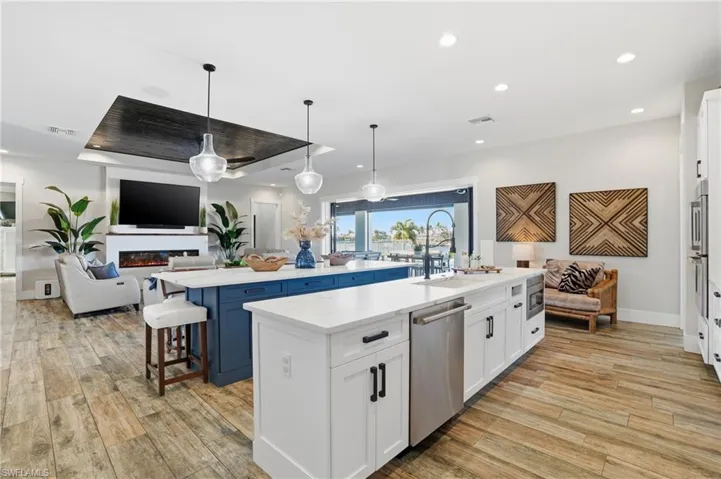 Kitchen with white cabinets, open floor plan, hanging light fixtures, recessed lighting, and a breakfast bar