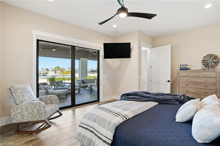 Bedroom with access to outside, wood tiled floors, recessed lighting, and a ceiling fan an ensuite bathroom