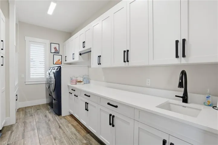 Laundry area with wood tiled floors, cabinet space, and washer and dryer