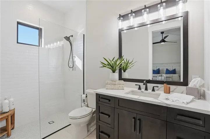 Bathroom featuring vanity, walk in shower, and ceiling fan