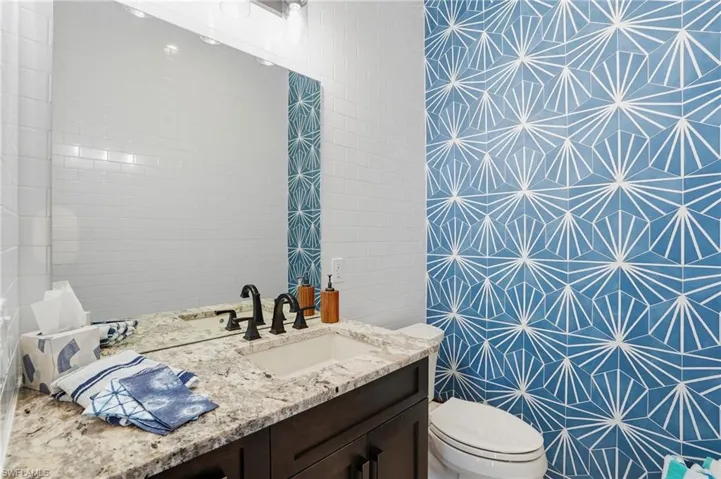 Pool area half bath featuring tile walls and vanity