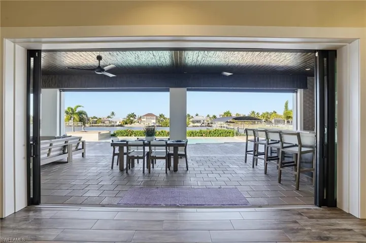 Impact glass sliders leading to outdoor dining featuring a water view, paver patio, rich cypress ceilings and automatic Kevlar role down screen
