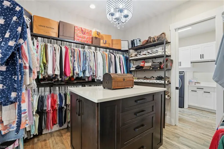 Spacious closet featuring a chandelier, light wood-style floors, and washer / clothes dryer