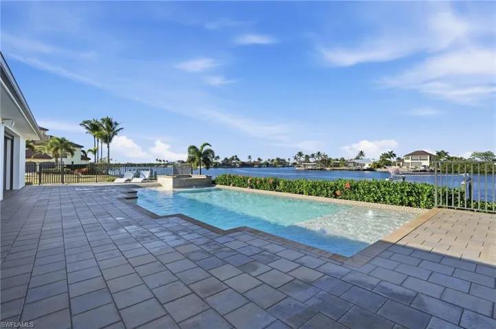 View of swimming pool with a patio area, a water view, and a pool with connected hot tub