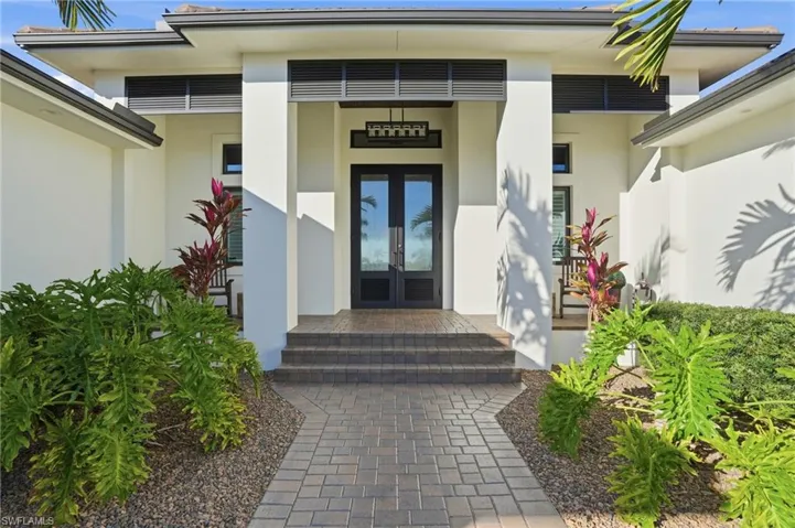 Doorway to property with french doors, stucco siding, and a porch