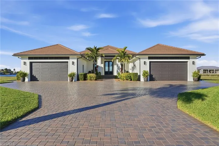 View of front facade with a garage, stucco siding, and decorative driveway
