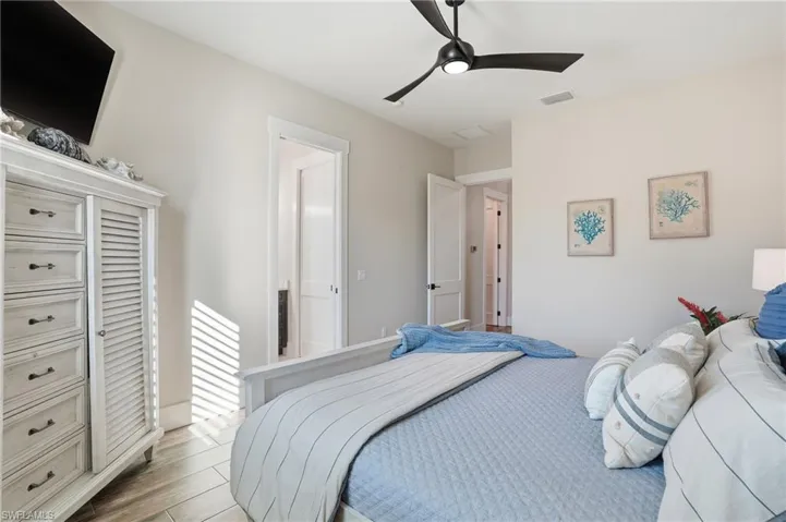 Bedroom with wood finished floors and a ceiling fan with ensuite bathroom