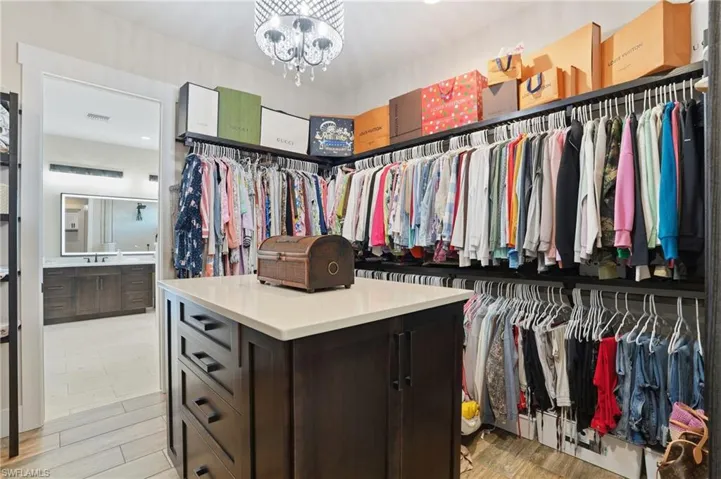 Spacious closet featuring a chandelier and light wood-style floors