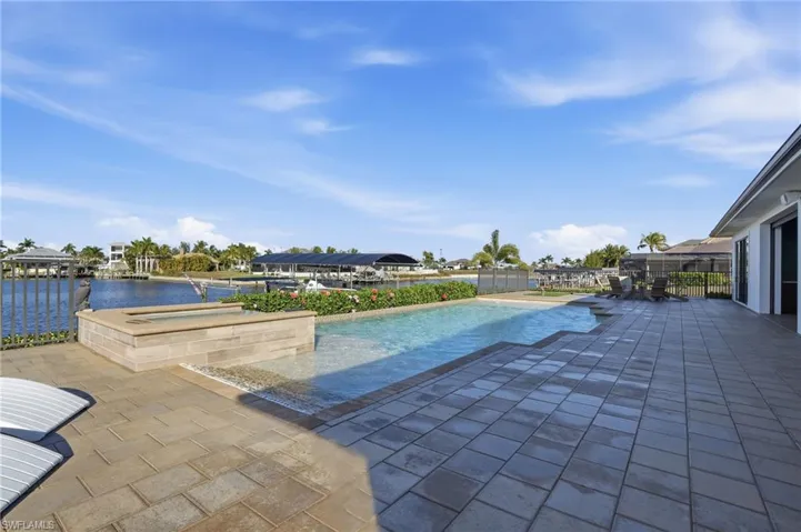 Outdoor pool with a patio area, a water view, and an outdoor hot tub