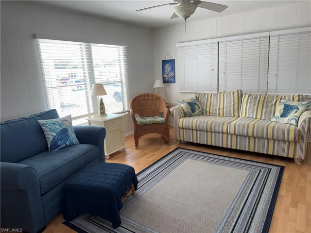 Living room with wood finished floors, wood walls, and a ceiling fan