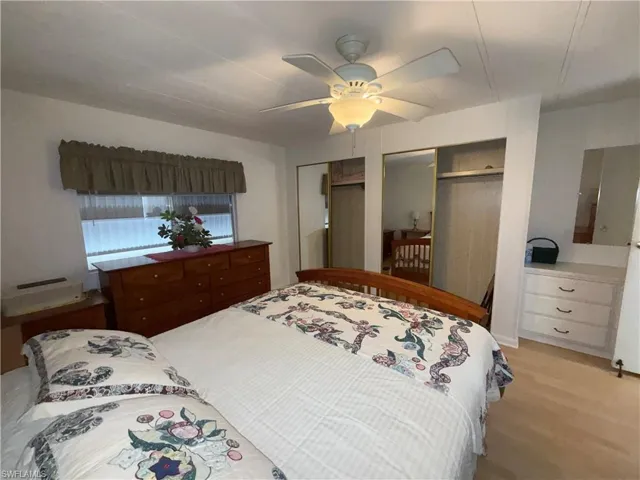 Bedroom with two closets, ceiling fan, and light wood-style flooring