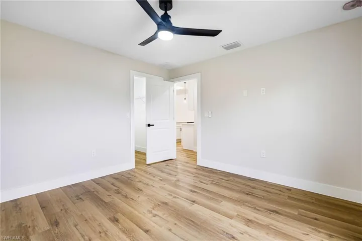 Unfurnished bedroom featuring a walk in closet, light wood-style floors, and a ceiling fan