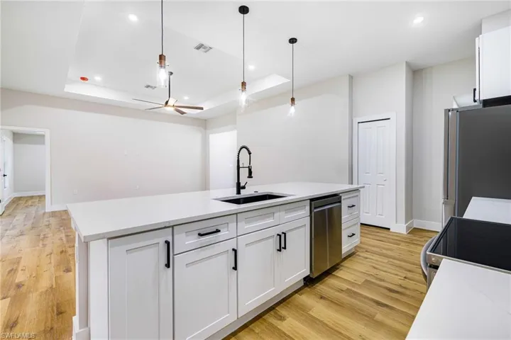 Kitchen with white cabinetry, decorative light fixtures, stainless steel appliances, light wood-style floors, and recessed lighting