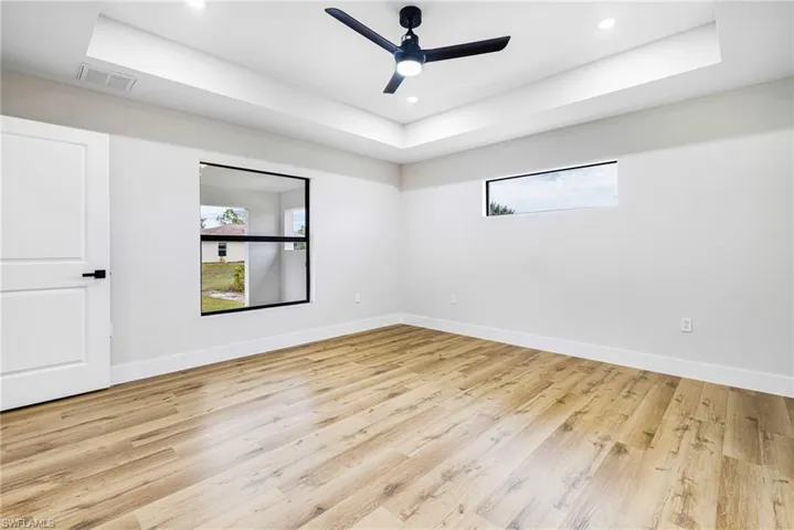 Unfurnished room with a raised ceiling, light wood-style floors, ceiling fan, and recessed lighting