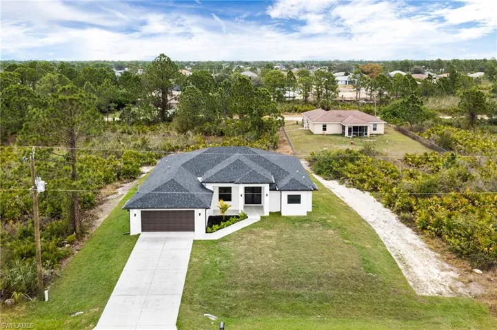 Aerial view of property and surrounding area featuring a tree filled landscape