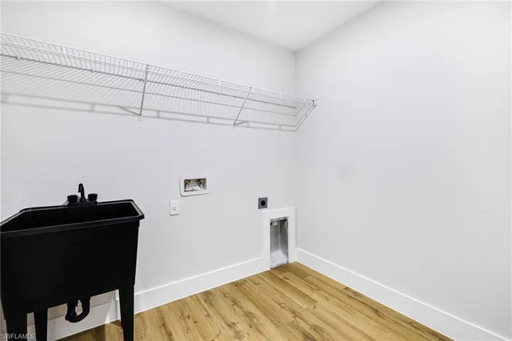Washroom with hookup for an electric dryer, wood finished floors, and hookup for a washing machine