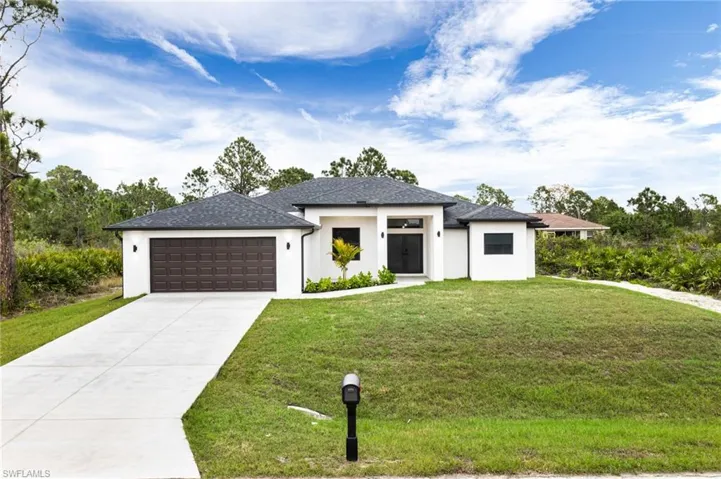 Prairie-style home featuring stucco siding, concrete driveway, a front yard, and an attached garage