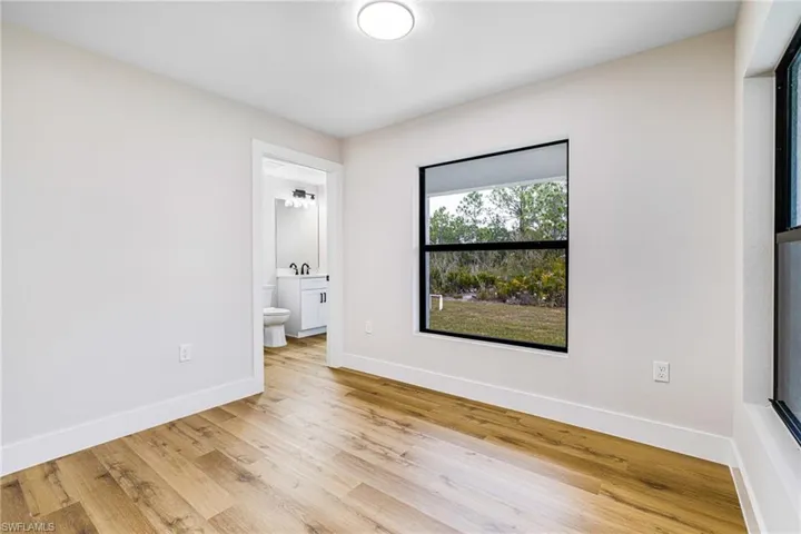 Unfurnished bedroom featuring light wood-style flooring and ensuite bathroom