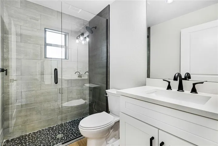 Full bathroom with vanity, a shower stall, and a textured wall