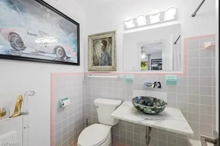 Bathroom featuring a vessel sink with a marble countertop, square tile walls, and a recessed medicine cabinet