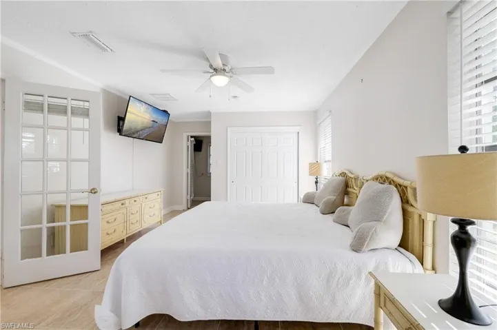 Bedroom with crown molding, a closet, light tile patterned floors, and ceiling fan