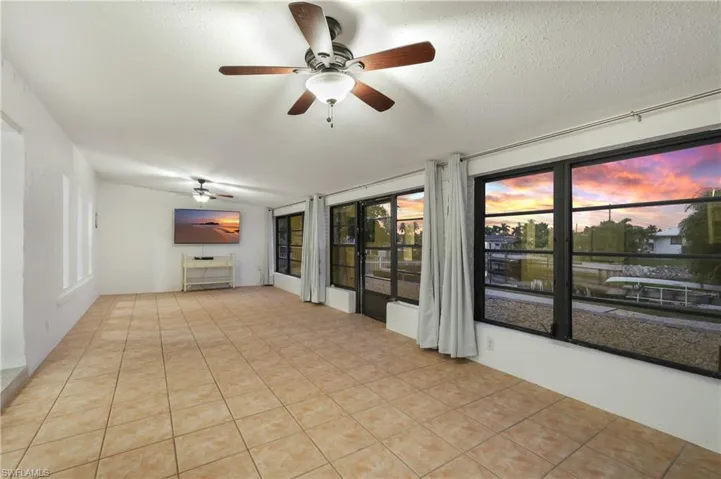 Unfurnished living room featuring light tile patterned flooring, a textured ceiling, and ceiling fan