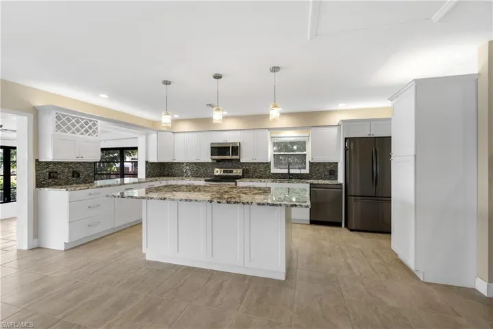 Kitchen with stone counters, tasteful backsplash, a kitchen island, and stainless steel appliances