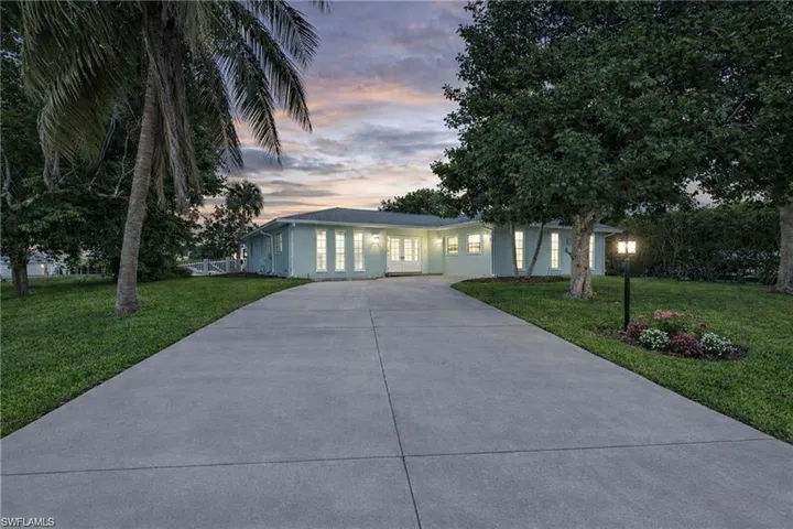 Ranch-style house with concrete driveway, a front lawn, and stucco siding