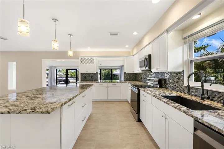 Kitchen with tasteful backsplash, stainless steel appliances, sink, light stone counters, and light tile patterned floors